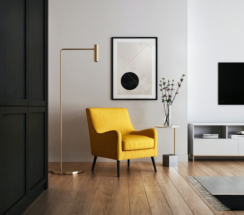 Minimalist living room with a mustard-yellow armchair, gold floor lamp, and abstract wall art